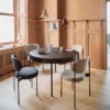 Round black dining table with six upholstered chairs in a peach-toned paneled room with pendant lights above.](https://)