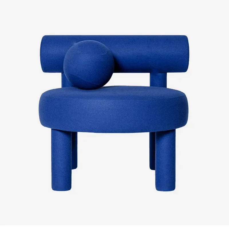 Gropius Low Accent Chair in bold blue upholstery with cylindrical legs, rounded seat, and geometric backrest on white background