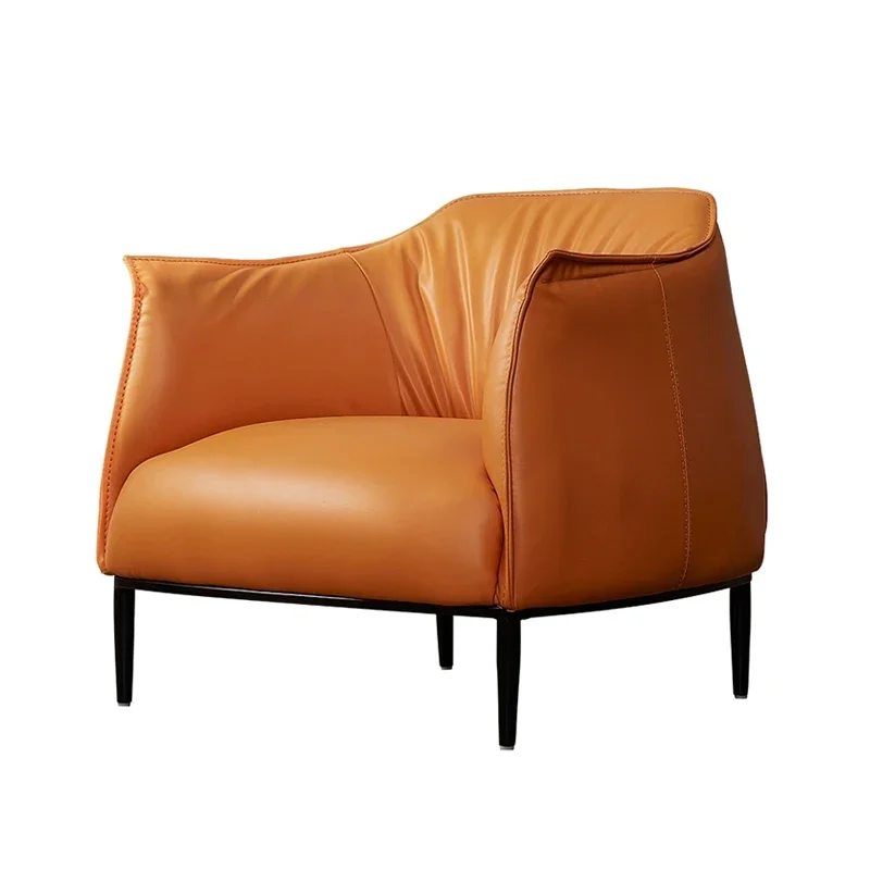 Archibald Armchair in tan leather with plush cushioned seat, sculpted armrests, and slim black legs on a white background