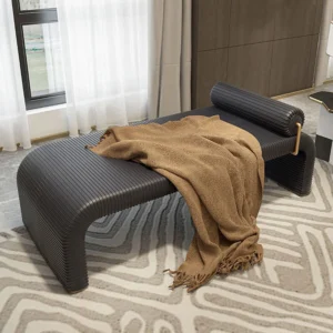 Cade Daybed Design Bench Slipper Chair in black ribbed leather with a brown throw blanket on a patterned rug.