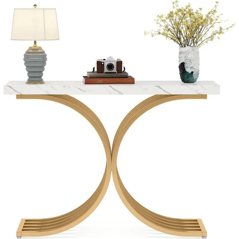 Entryway Console Wave: Modern white marble top on gold C-shaped legs, styled with a lamp, camera, books, and flowers.
