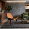 Modern living room with a curved orange lounge chair, green sofa, and arc floor lamp on a gray rug. A wooden cabinet and a tall plant sit against the wall.