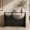 Contemporary black console table with two semicircular cutouts, topped with a vase of greenery and a small book stack.