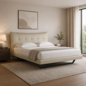 A modern beige upholstered bed with tufted headboard in a neutral bedroom, flanked by a wooden nightstand and lamp, facing a large window.