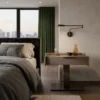 Modern bedroom with a floating nightstand, wall-mounted lamp, and a view of the city skyline through large windows.