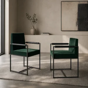 Two dark-green velvet armchairs with black metal frames facing each other in a minimalist living room on a beige rug.
