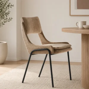 Beige upholstered dining chair with black metal legs beside a wooden round table in a bright, minimalist room