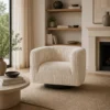 Cream ribbed swivel chair in a neutral living room with a round coffee table, plants, books, and a fireplace on the right.