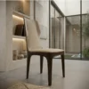 Wooden chair with beige upholstered back and seat in a modern glass-walled room.