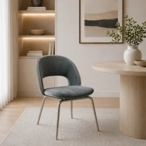 Blue upholstered chair with metal legs beside a round wooden table in a softly lit, modern living room.