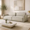 Cream-colored modern sofa in a sunlit living room with a marble coffee table, potted plant, and abstract wall art.