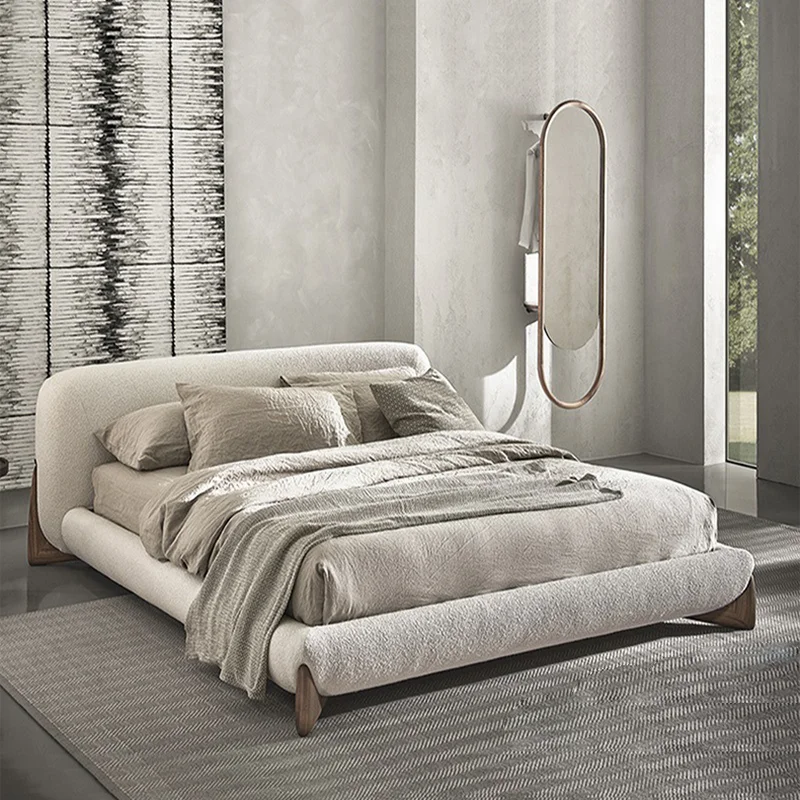 1-96458 Neutral-toned modern bedroom with a low, upholstered bed and fluffy bedding, plus a tall oval mirror on the wall.