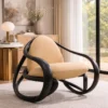 Beige upholstered lounge chair with a thick black curved frame in a bright living room by large windows.