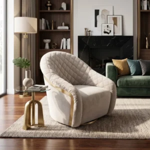 A modern living room with a plush beige quilted armchair, glass side table with a gold base, and a potted plant on the table next to a window. In the background, a dark fireplace and green sofa with colorful cushions sit against a bookshelf wall and framed artwork above the mantle.