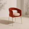 Red upholstered armchair with a curved back and gold metal legs in a neutral room.