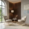 Two beige upholstered lounge chairs with gold frames face a small round table in a stylish living nook with a wood slat wall and warm lighting from a wall lamp.