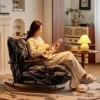 Woman in a cream sweater sits in a cushioned rocking chair, playing a ukulele in a cozy living room.
