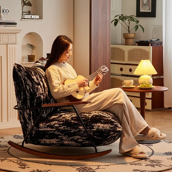 Woman in a cream sweater sits in a cushioned rocking chair, playing a ukulele in a cozy living room.