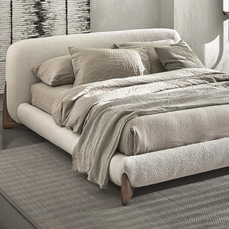 5-96458 Neutral-toned upholstered bed with rounded headboard and low-profile footboard on a striped rug.