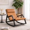 Tan leather lounge chair with a black metal rocking frame in a bright living room, next to a round side table and a tall plant.