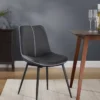Gray upholstered dining chair with black legs beside a wooden table set with two wine glasses in a modern dining room.