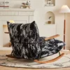 Modern rocking chair with black-and-white textured upholstery and wooden rockers in a cozy living room with a fireplace beside it.