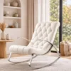 White cushioned lounge chair with tufted back and curved metal frame in a bright living room.