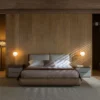 Hotel-style bedroom with a wood-paneled accent wall, centered king bed, and twin nightstands with warm wall lamps.