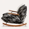 Rocking chair with wooden arms and a black‑white patterned cushion, tilted on curved wooden rockers showing a rocking angle.