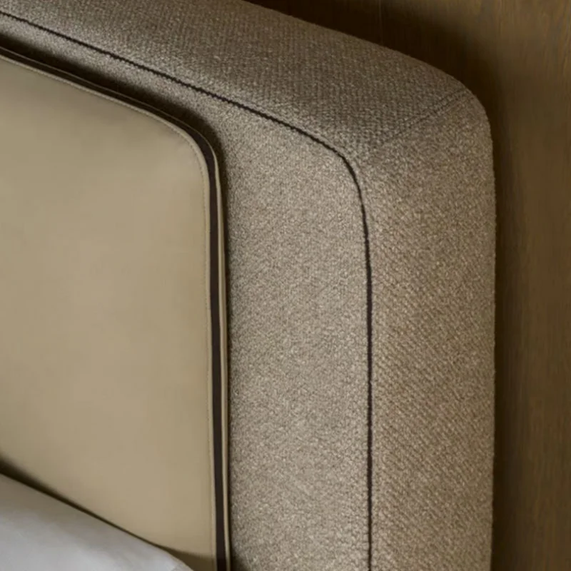 Close-up of a beige upholstered sofa corner showing a rounded arm and a contrasting panel.